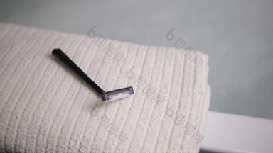 男人的手的地方一次性剃须刀毛巾浴室黑色的剃须刀白色毛巾模糊背景